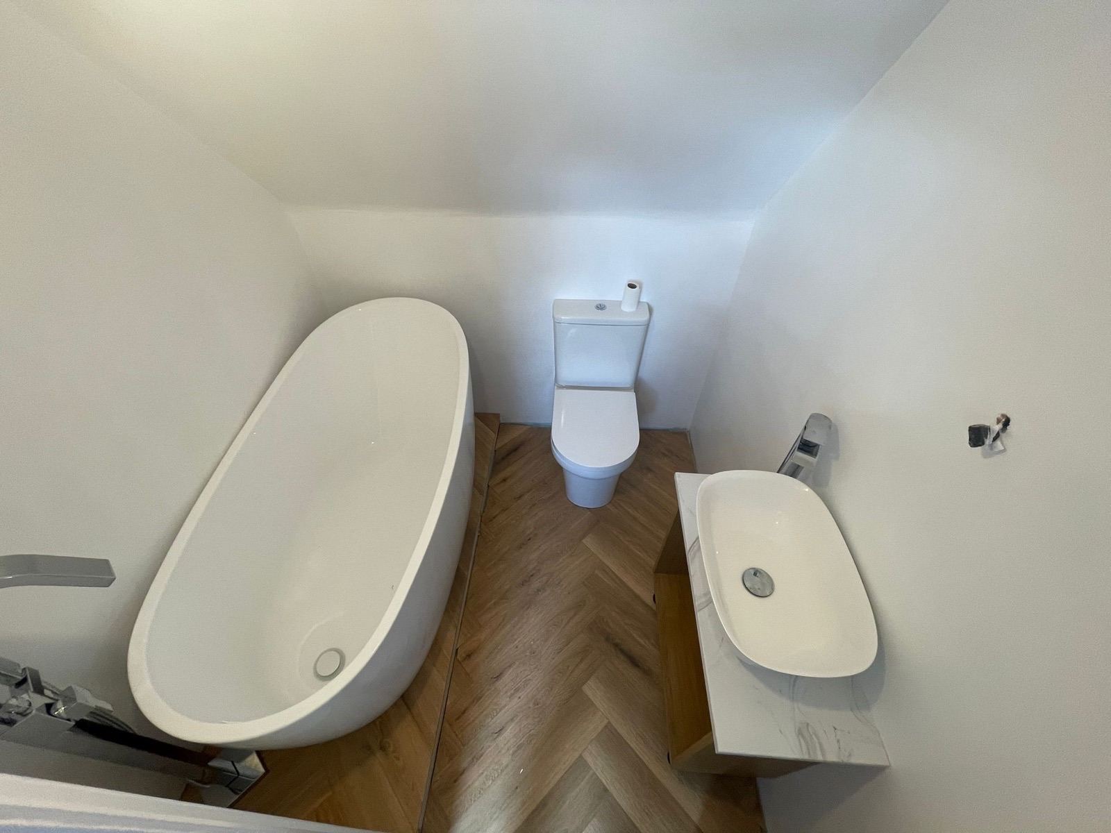 Bathroom with a freestanding bath and herringbone floor after renovation