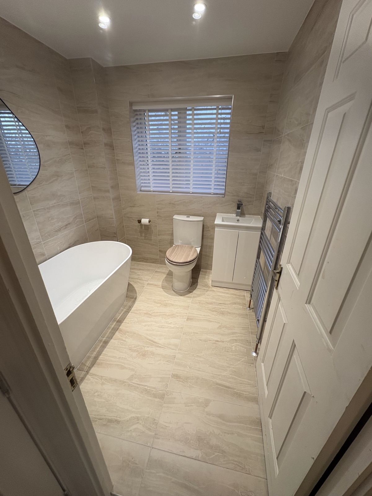 Bathroom with a bath, vanity unit and heated towel rail after renovation