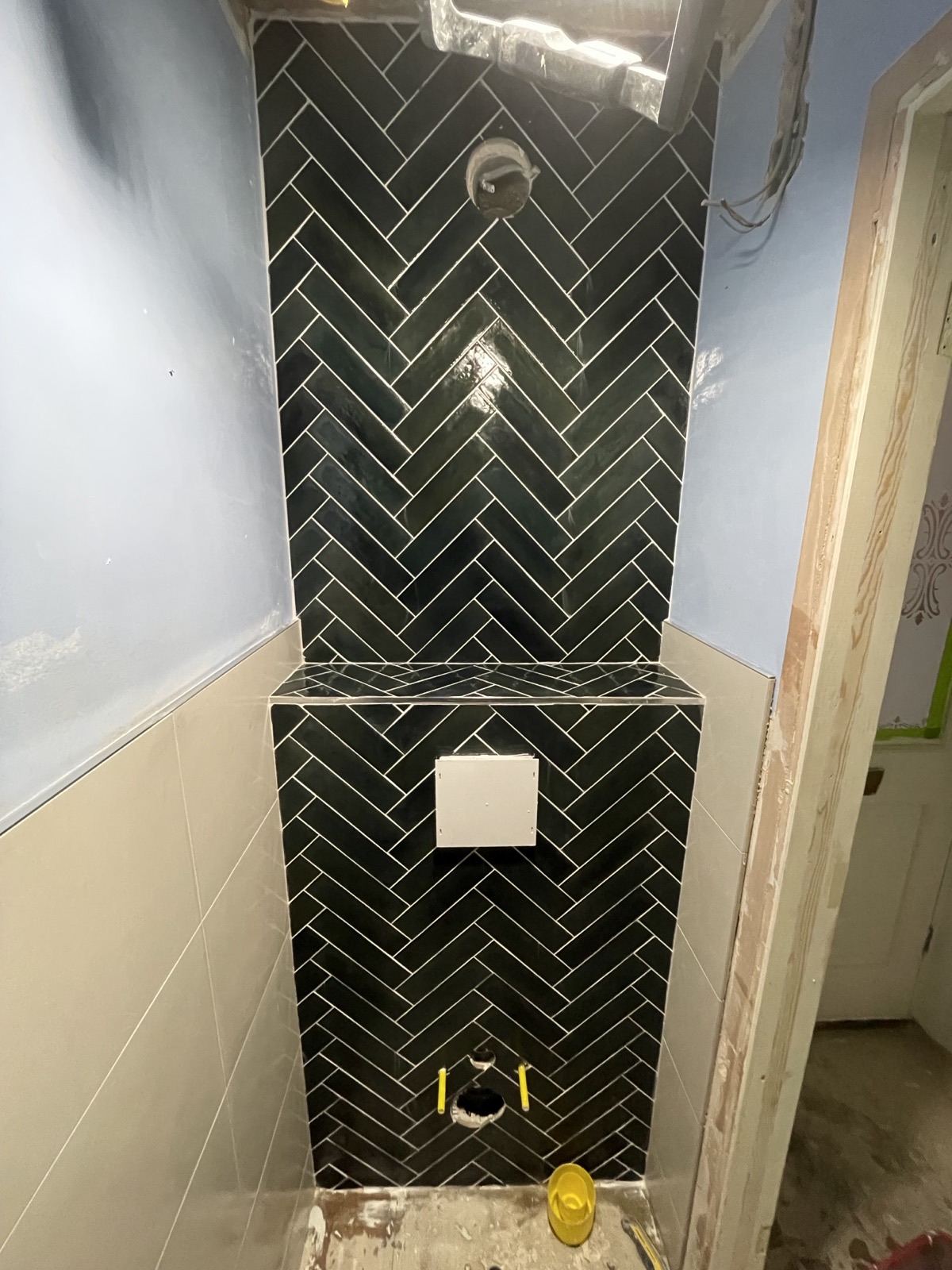Black herringbone tiling around a wall-hung toilet