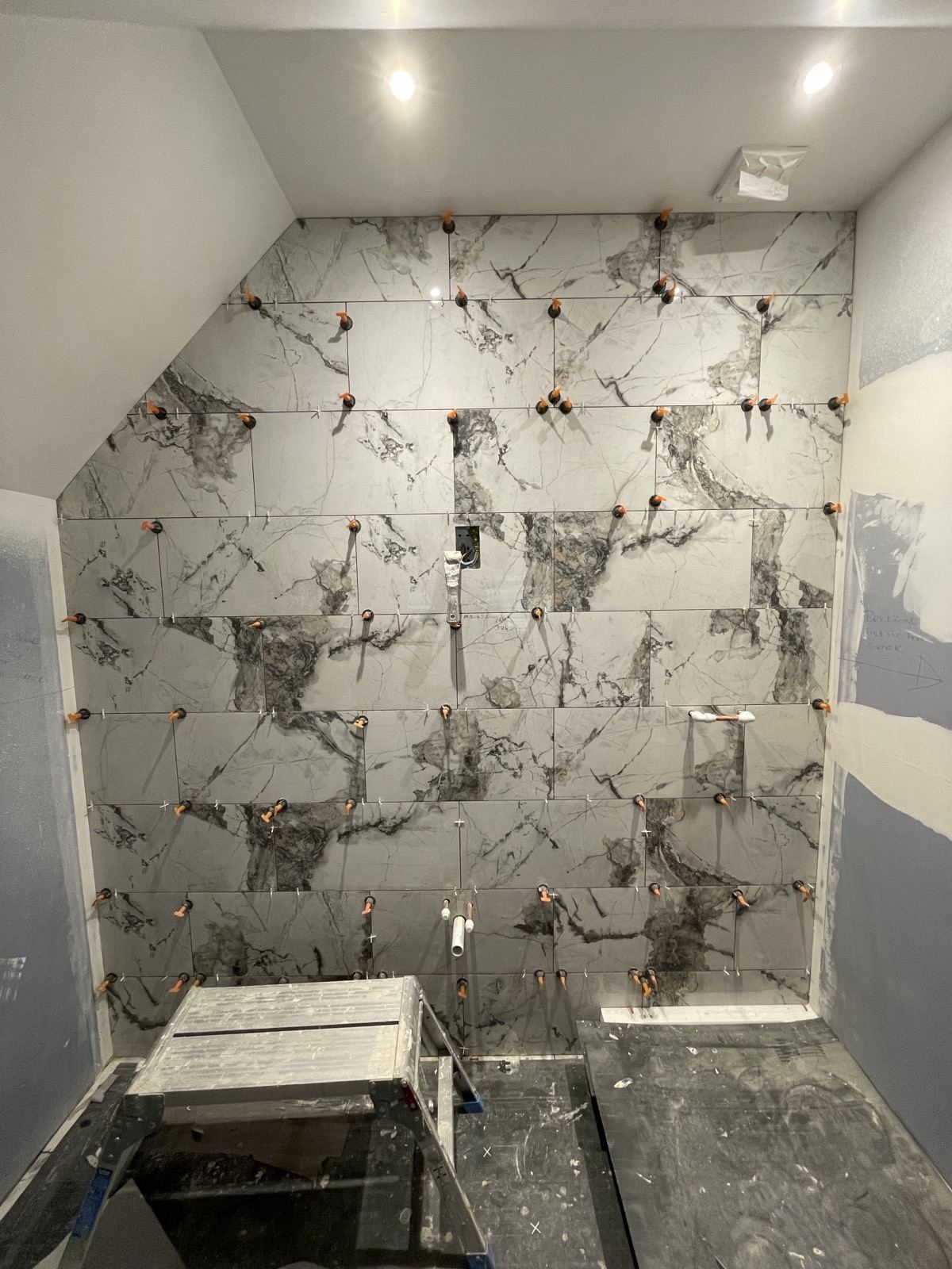 Marble-effect porcelain wall tiles being fitted in a shower